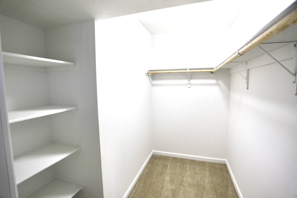 a walk in closet with white walls and shelves and