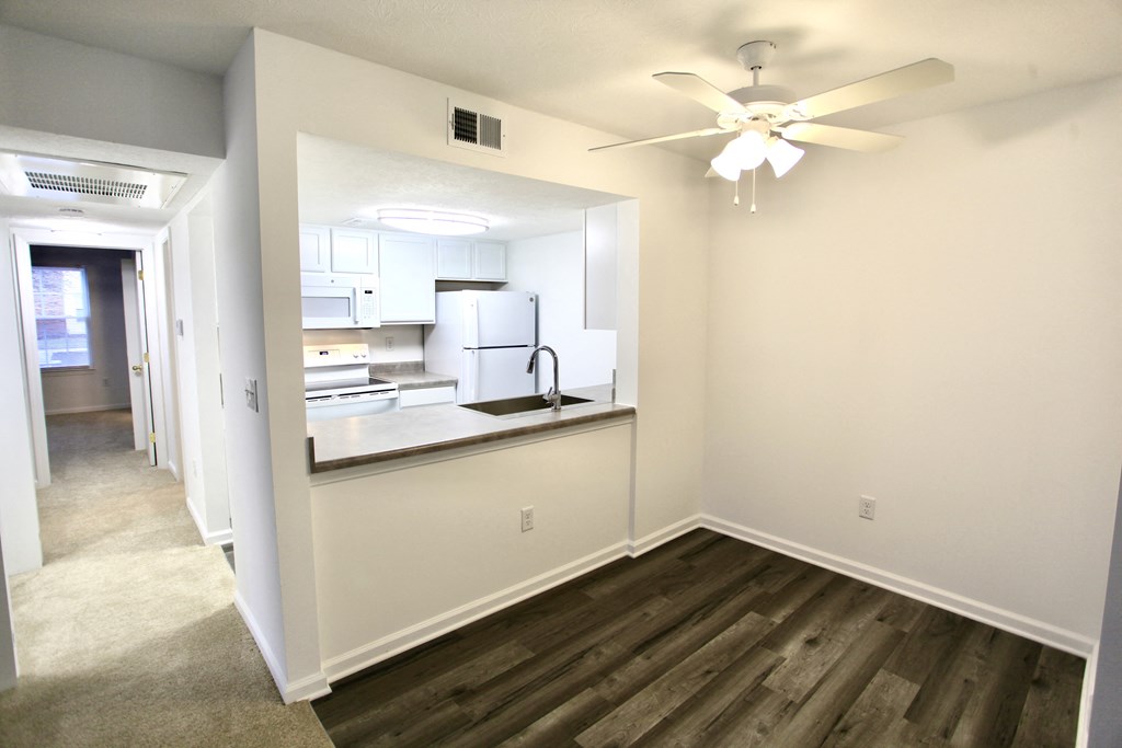 an empty room with a kitchen and a ceiling fan