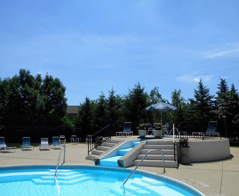 a swimming pool and patio with chairs and an umbrella