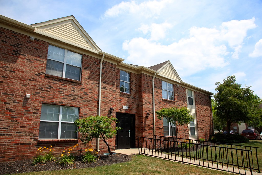 the front of a brick apartment building with a black fence