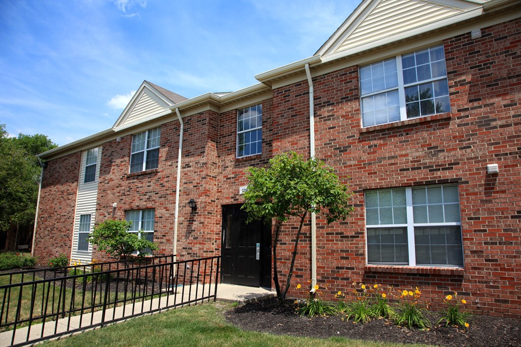 the front of a brick house with a black wrought iron fence