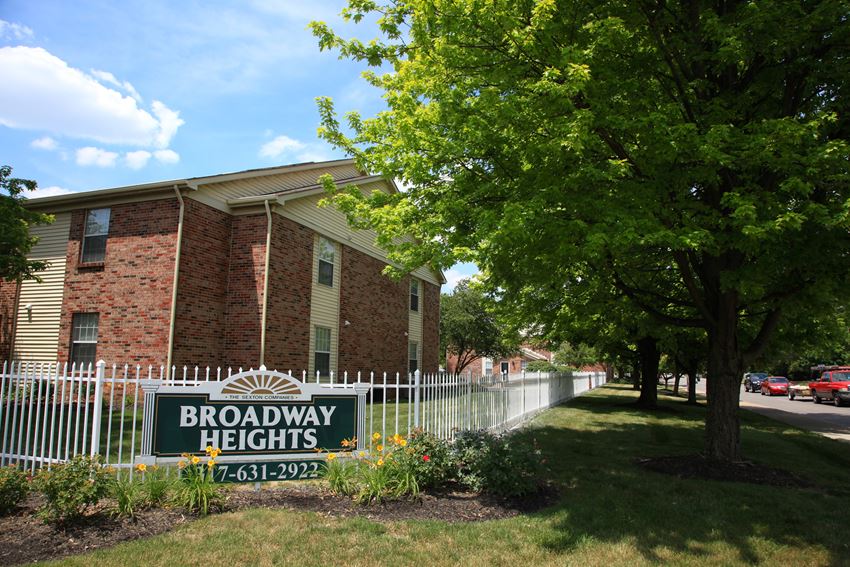 a building with a broadway heights sign in front of a white fence