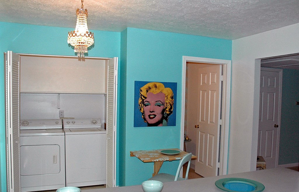 a kitchen with a washer and dryer and a blue wall with a painting