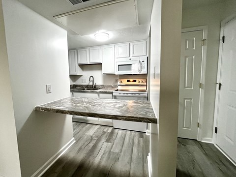 A kitchen with a marble countertop and white cabinets.