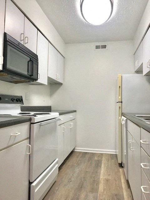 an empty kitchen with white appliances and a microwave