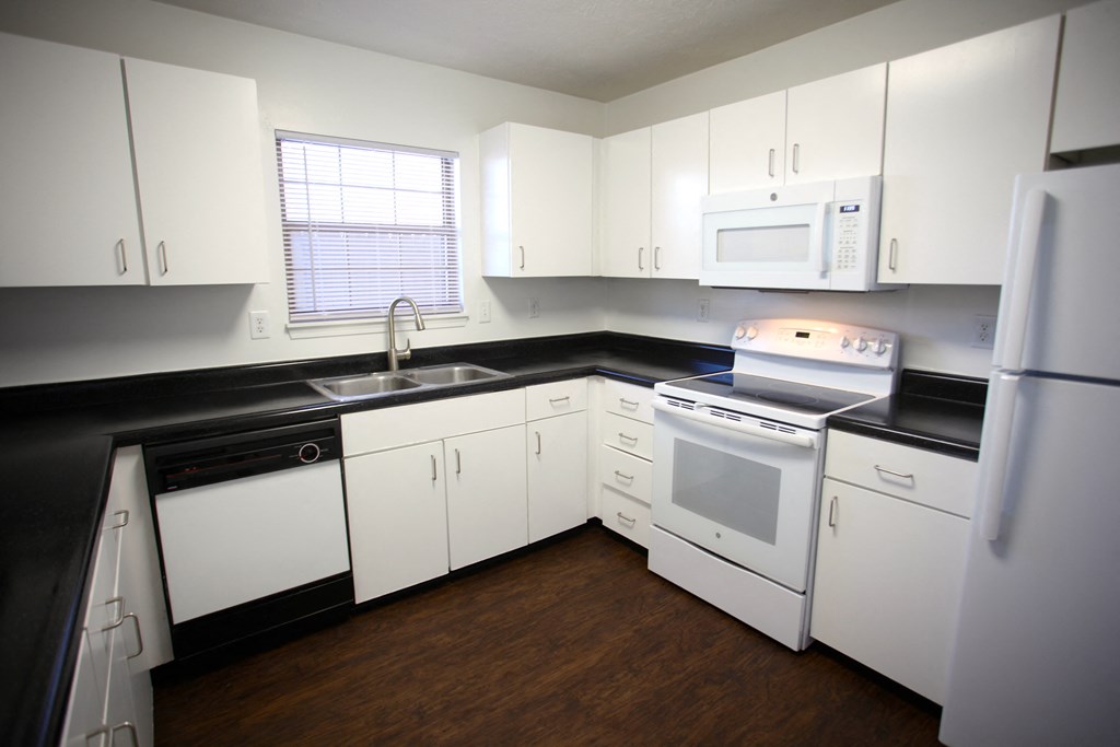 an empty kitchen with white appliances and white cabinets