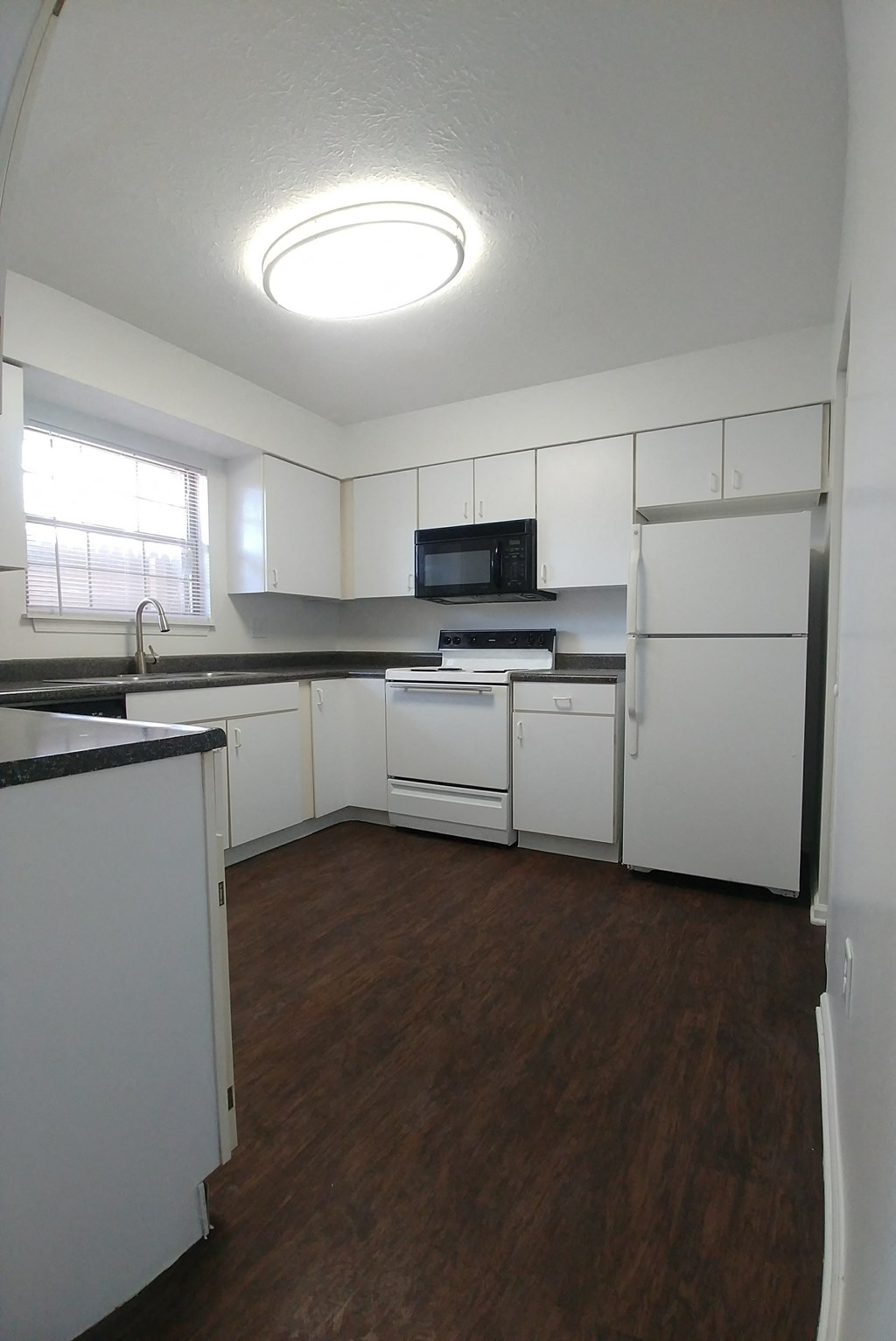 an empty kitchen with white appliances and white cabinets