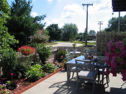 a patio with a table and chairs in a garden
