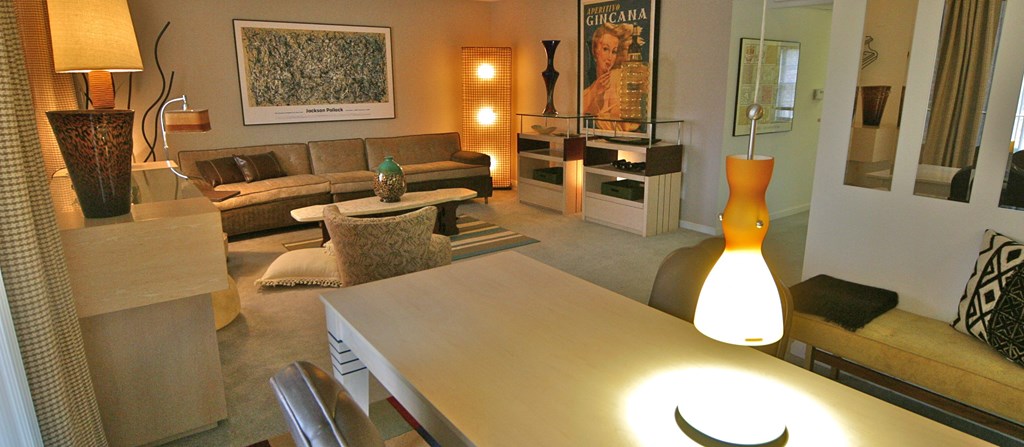 a living room and dining room with a table and a lamp