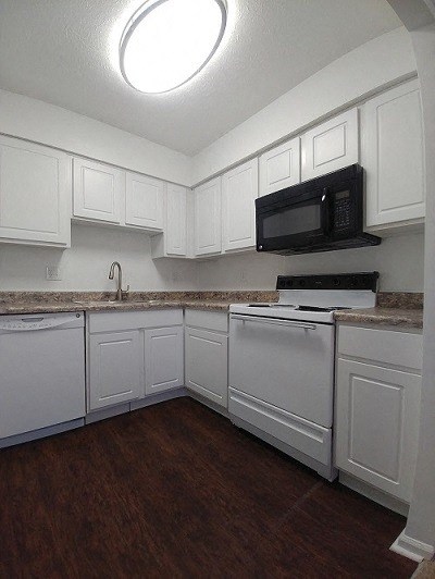 an empty kitchen with white cabinets and a microwave