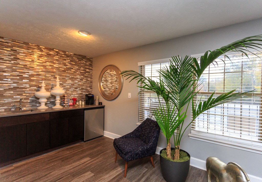 a living room with a plant and a kitchen