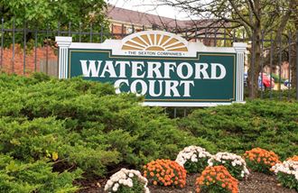 the sign for waterford court in front of plants and flowers