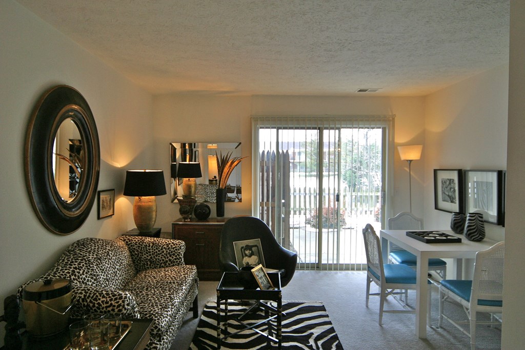 a living room with leopard print furniture and a sliding glass door to a balcony