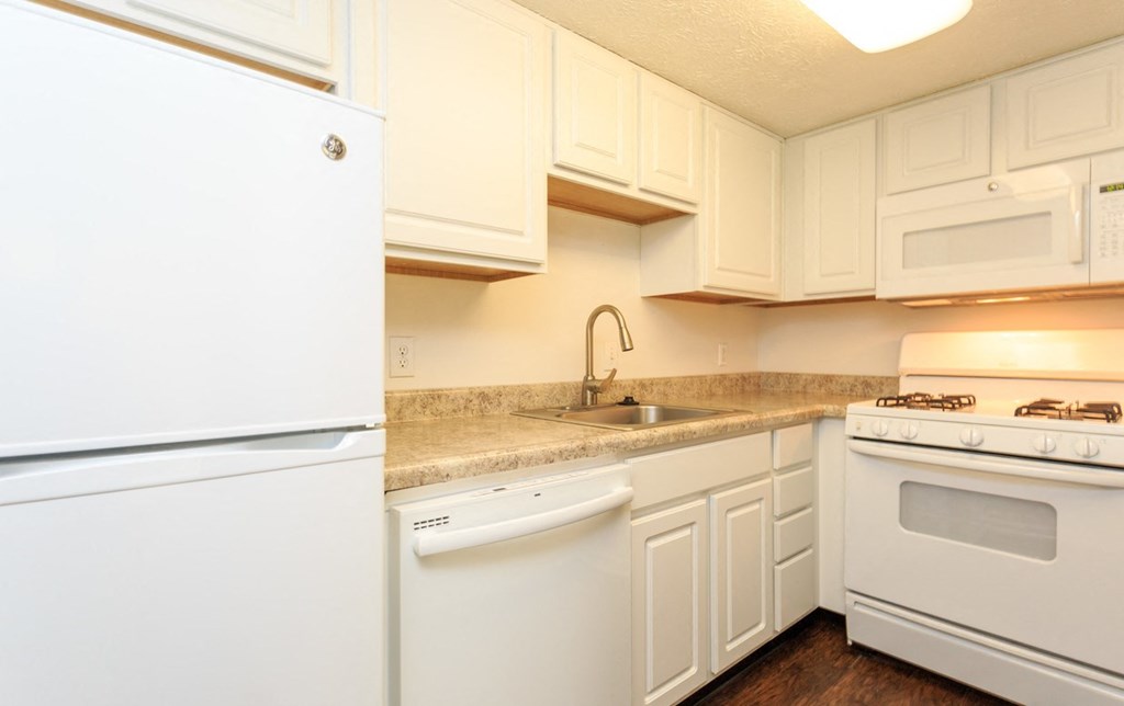 a kitchen with white appliances and granite counter tops and white cabinets
