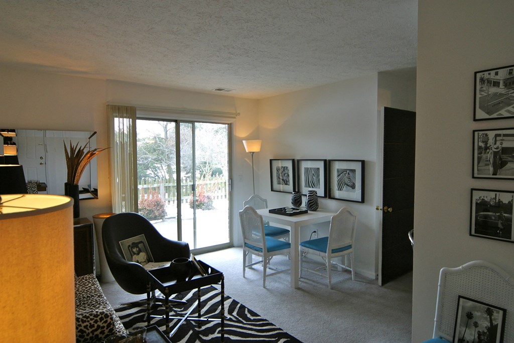 a living room with a desk and chairs and a sliding glass door