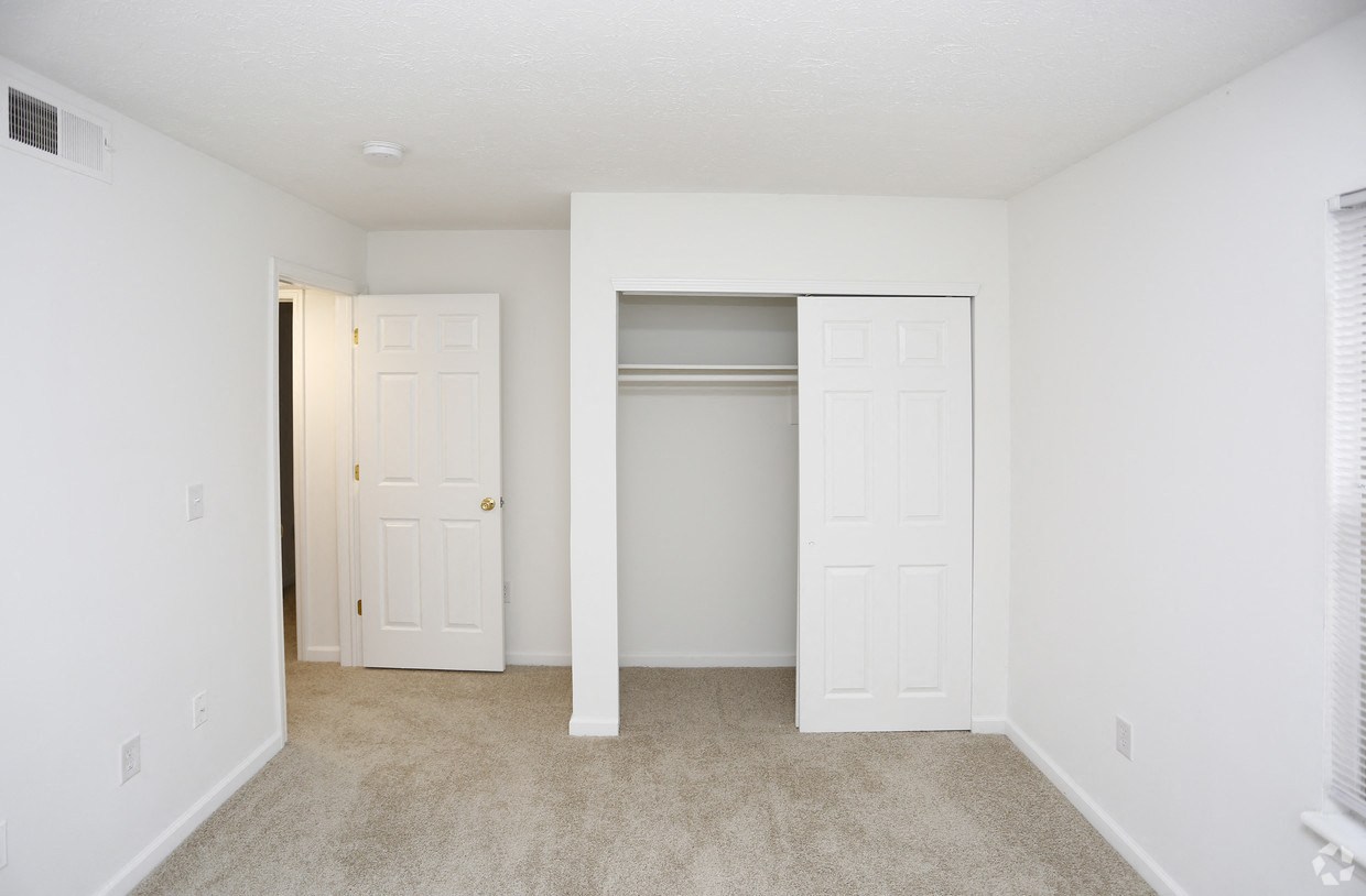 an empty bedroom with two doors and a closet