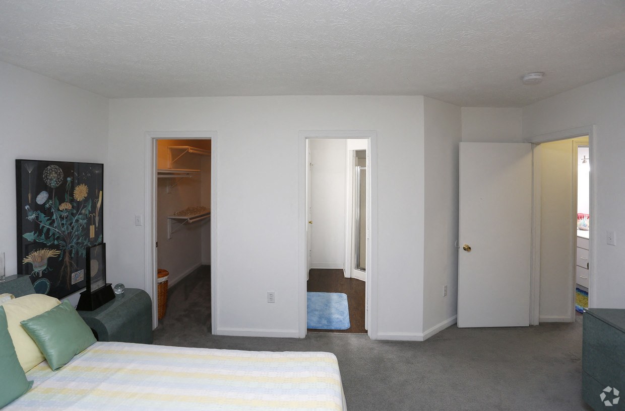 a bedroom with a bed and a closet and a living room