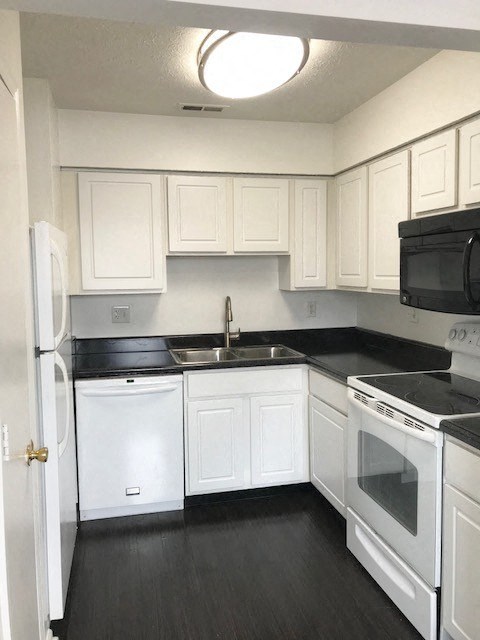 an empty kitchen with white cabinets and black counter tops