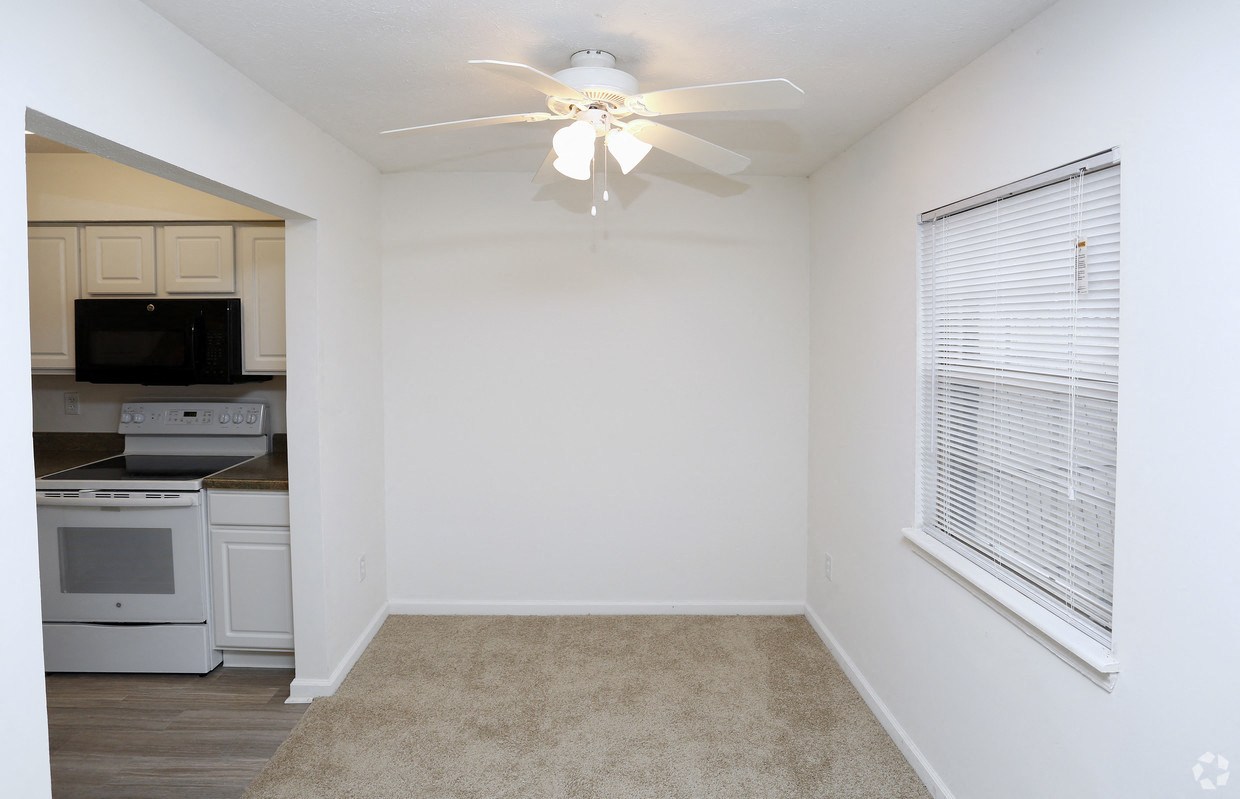 an empty kitchen with a ceiling fan and a window