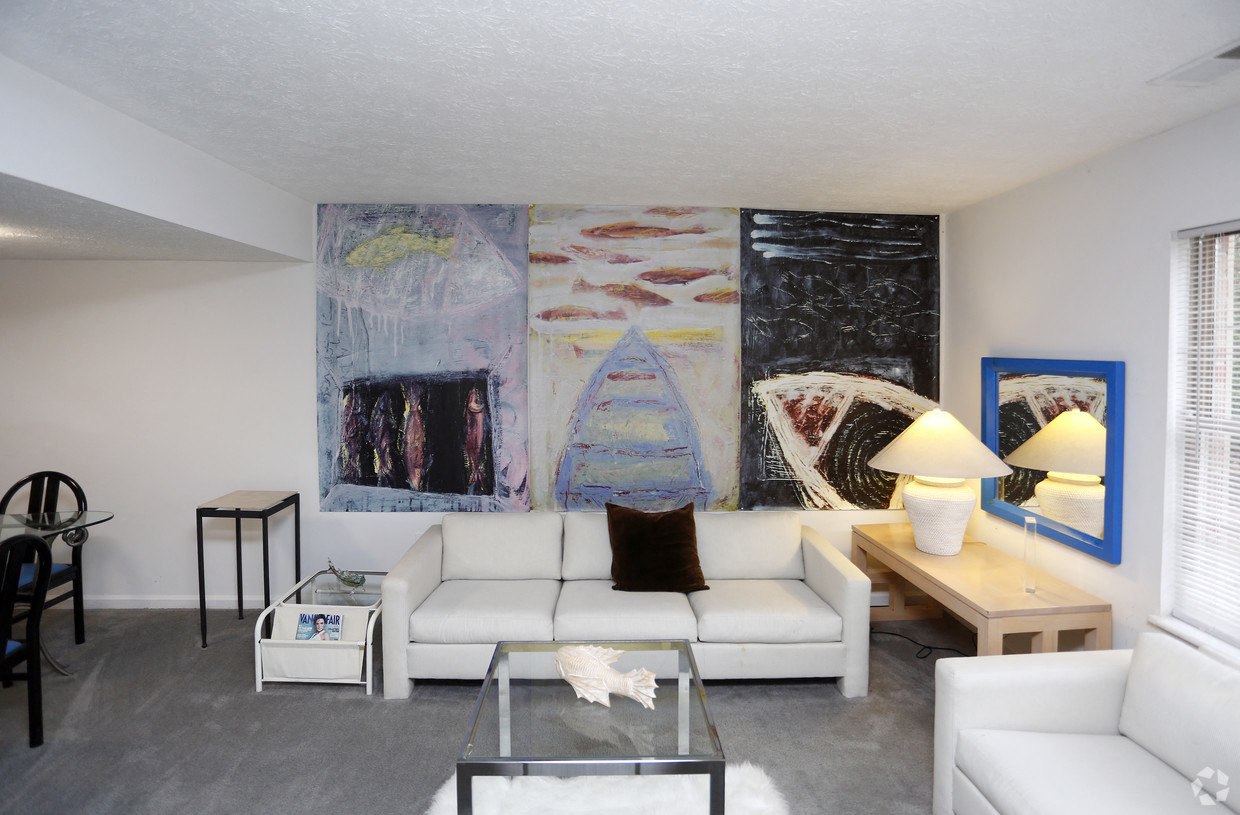 a living room with white furniture and a large painting on the wall