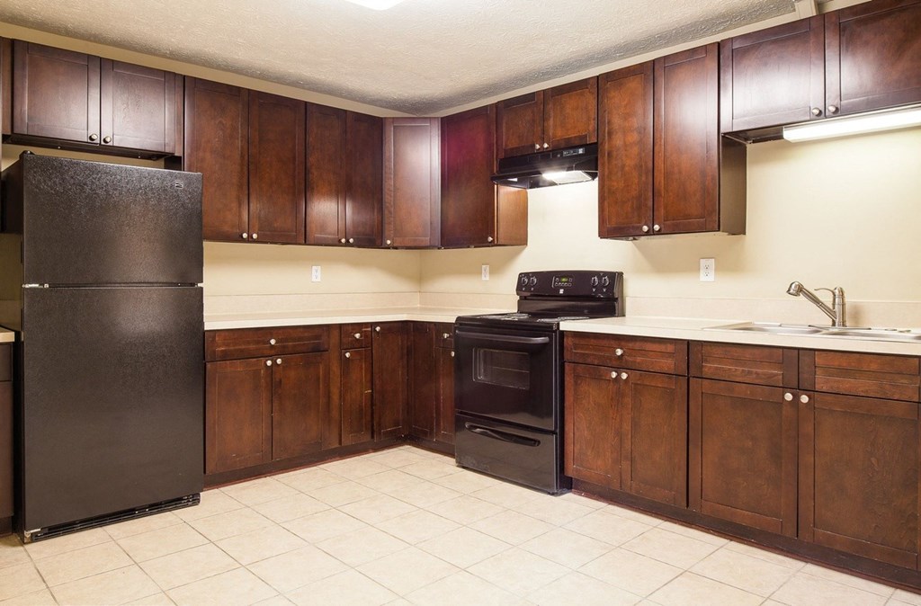a kitchen with wooden cabinets and a black refrigerator