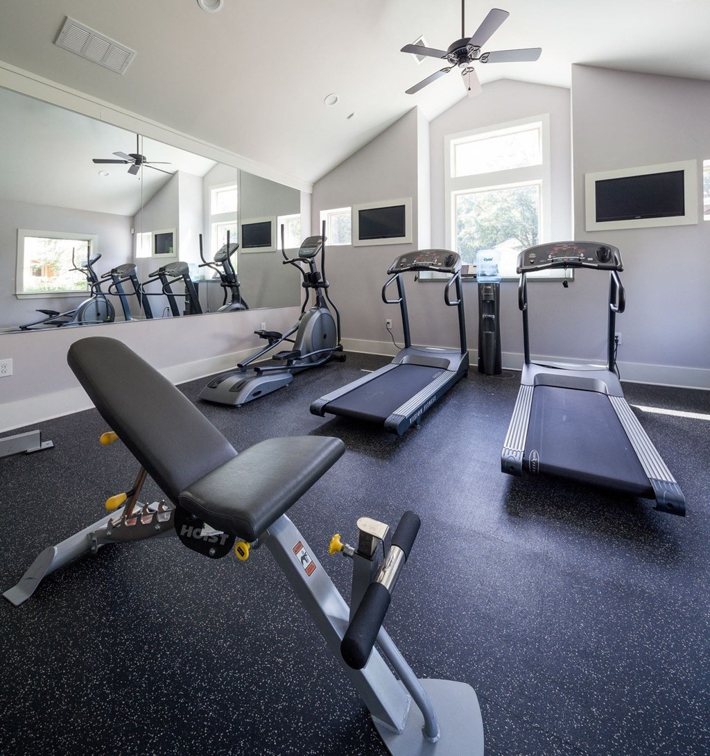 a gym with treadmills and other exercise equipment in a room with a window