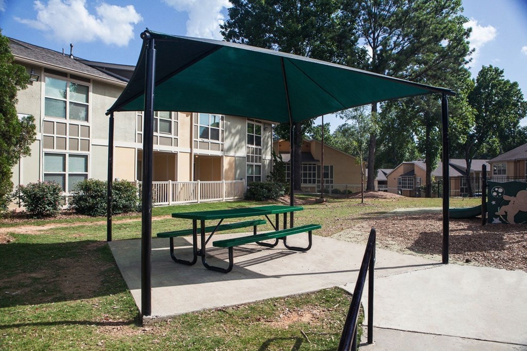 a picnic shelter with a picnic table in front of an apartment building