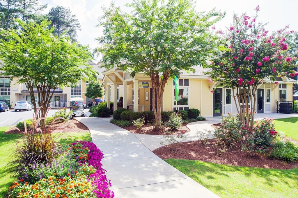 a building with a sidewalk and trees in front of it