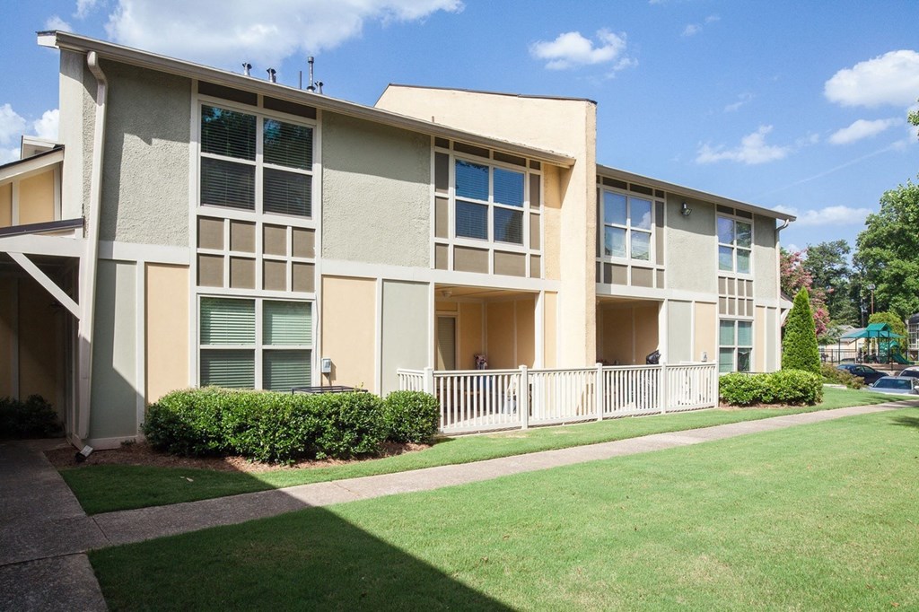 an apartment building with a green lawn and a sidewalk