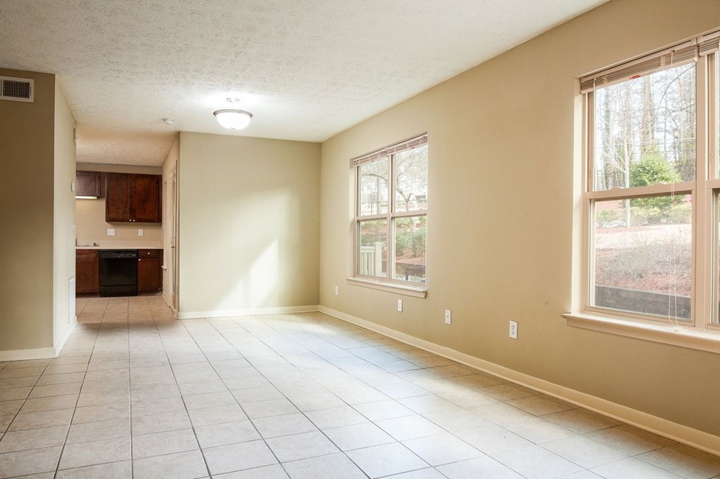 an empty living room with large windows and a tiled floor