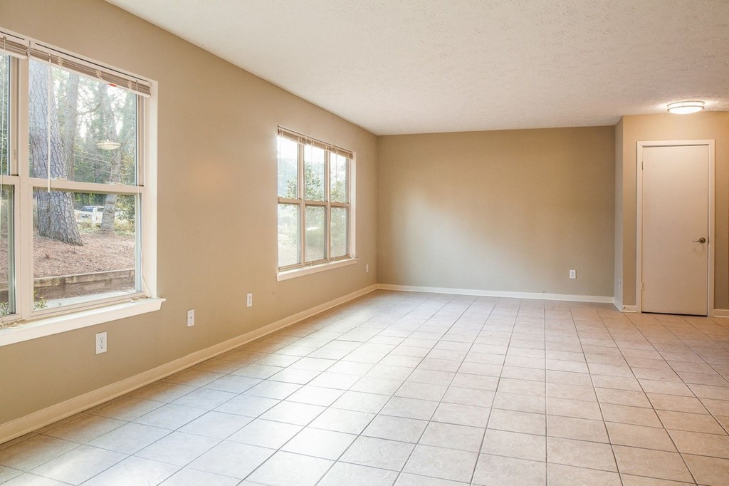 an empty living room with large windows and a tiled floor