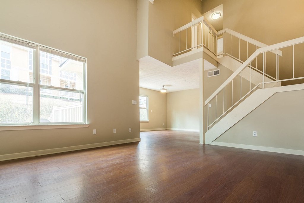an empty living room with a staircase and a large window