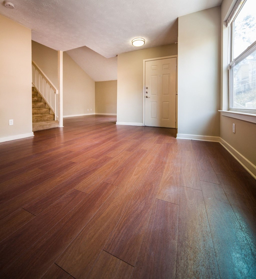 an empty living room with wooden floors and a door