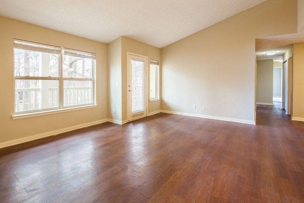 an empty living room with wood flooring and a large window
