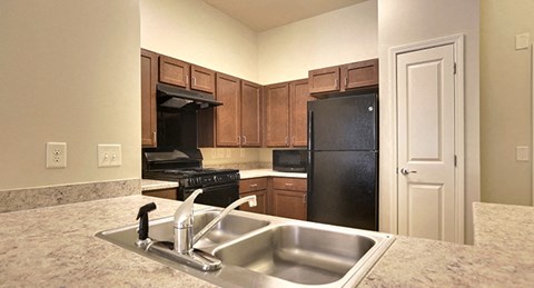 a kitchen with a sink and a black refrigerator