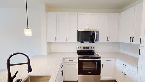 A kitchen with white cabinets and a black stove top oven.