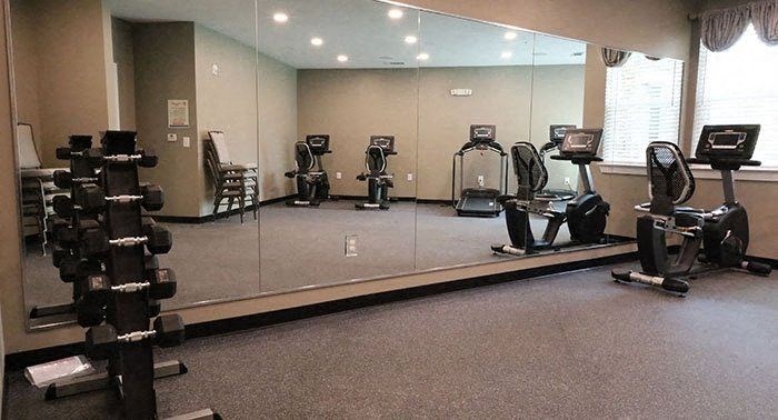 a gym with a mirrored wall with weights on it