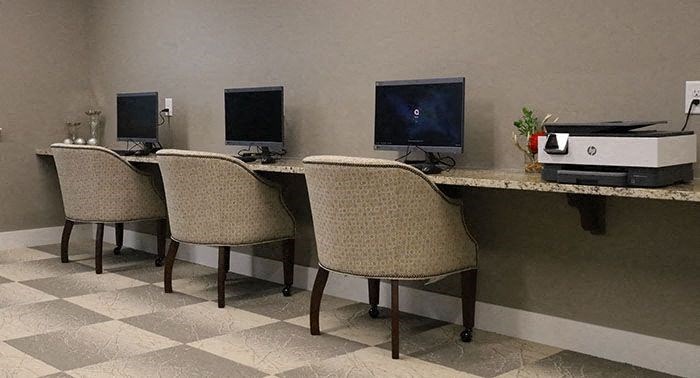 three chairs in front of three computers on a desk