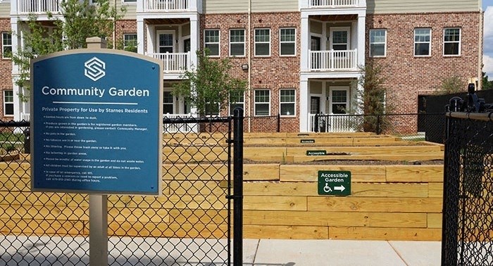 a community garden sign on a fence in front of an apartment building