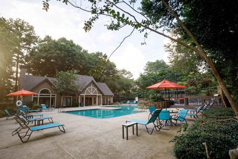 a swimming pool with chairs and umbrellas in front of a house decatur luxury living