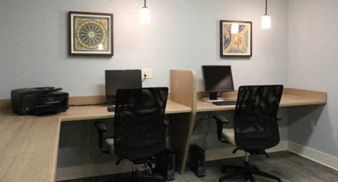 a desk with two computers and two chairs in a room
