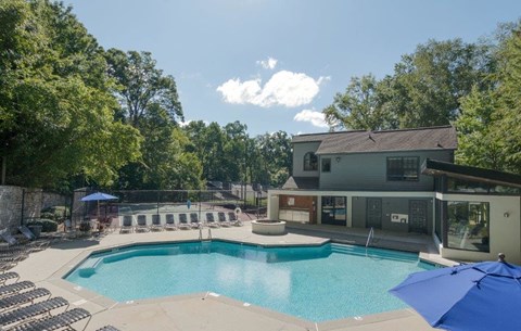 A large swimming pool surrounded by trees and a building in the background.