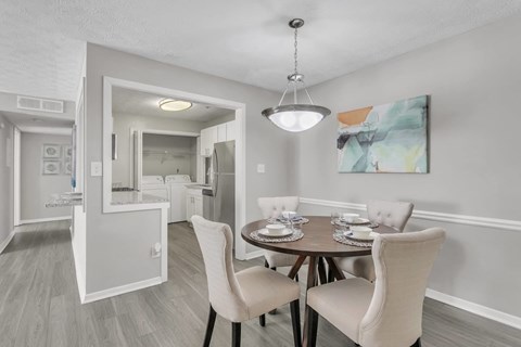 A dining room with a table set for two and a painting on the wall.