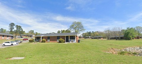 the front of a house with a grassy yard and a parking lot
