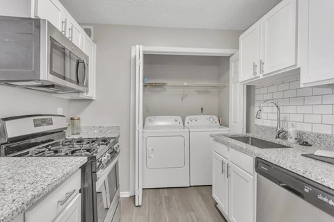 A kitchen with white cabinets and appliances.
