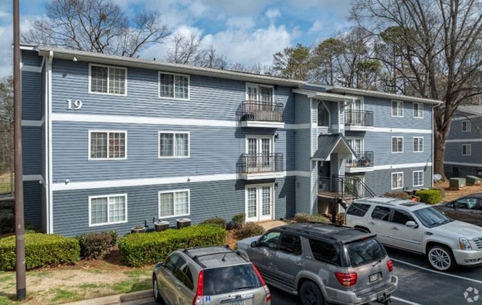 a blue apartment building with cars parked in a parking lot