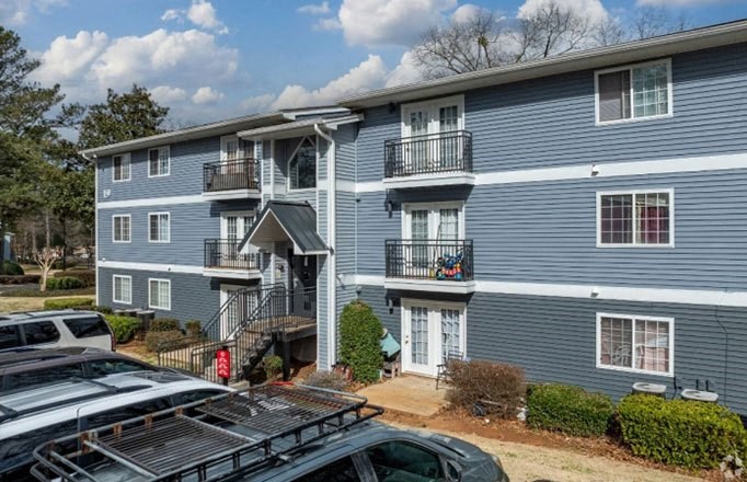 a blue apartment building with cars parked in front of it