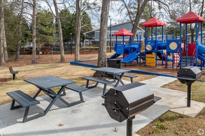 a playground with a picnic table and a grill