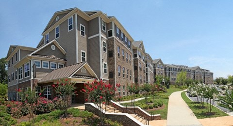 an exterior view of an apartment building with a walkway and gardens