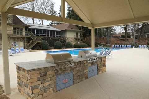 a covered patio with a barbecue grill next to a pool